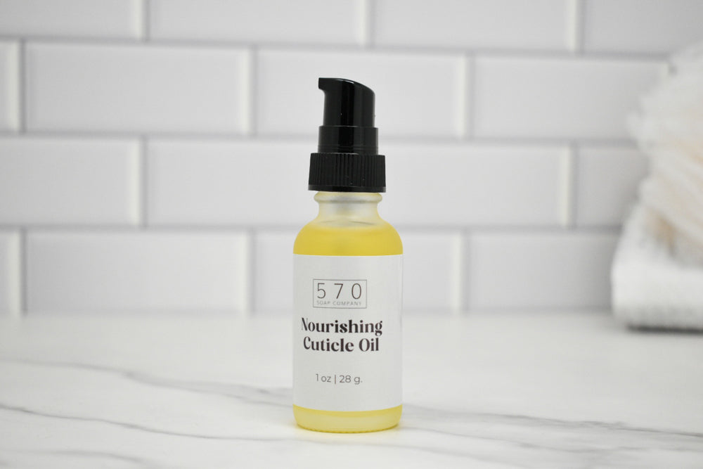 Bottle of 570 Nourishing Cuticle Oil on a white surface with a tiled wall background