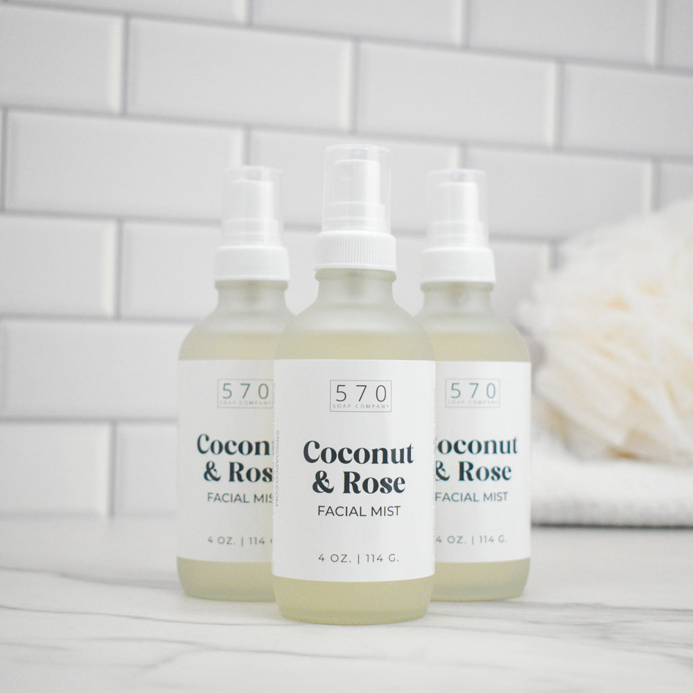 Three bottles of 570 Coconut & Rose Facial Mist on a bathroom counter with a tiled wall background.