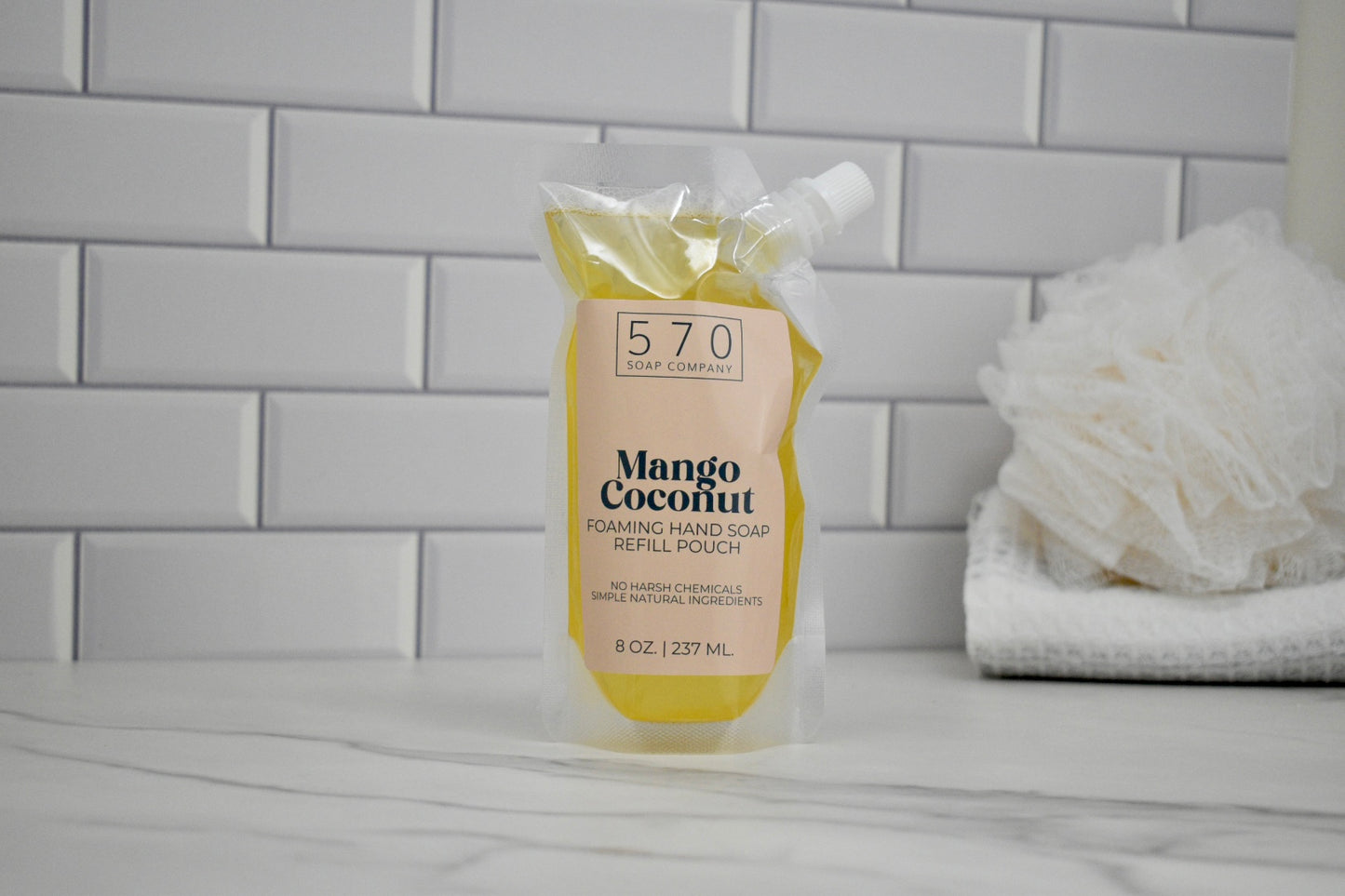 Hand soap bottle labeled '570' with 'Mango Coconut' scent on a bathroom counter.
