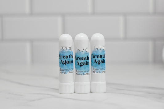 Three white tubes labeled with the brand 570 Soap Co. and identified as Nasal Inhalers stand upright on a marble surface, promising natural relief. Positioned against a white tiled background, these inhalers offer the soothing benefits of essential oils.