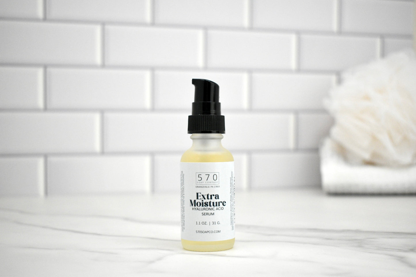 Bottle of 57.0 Extra Moisture Serum on a white tiled bathroom counter