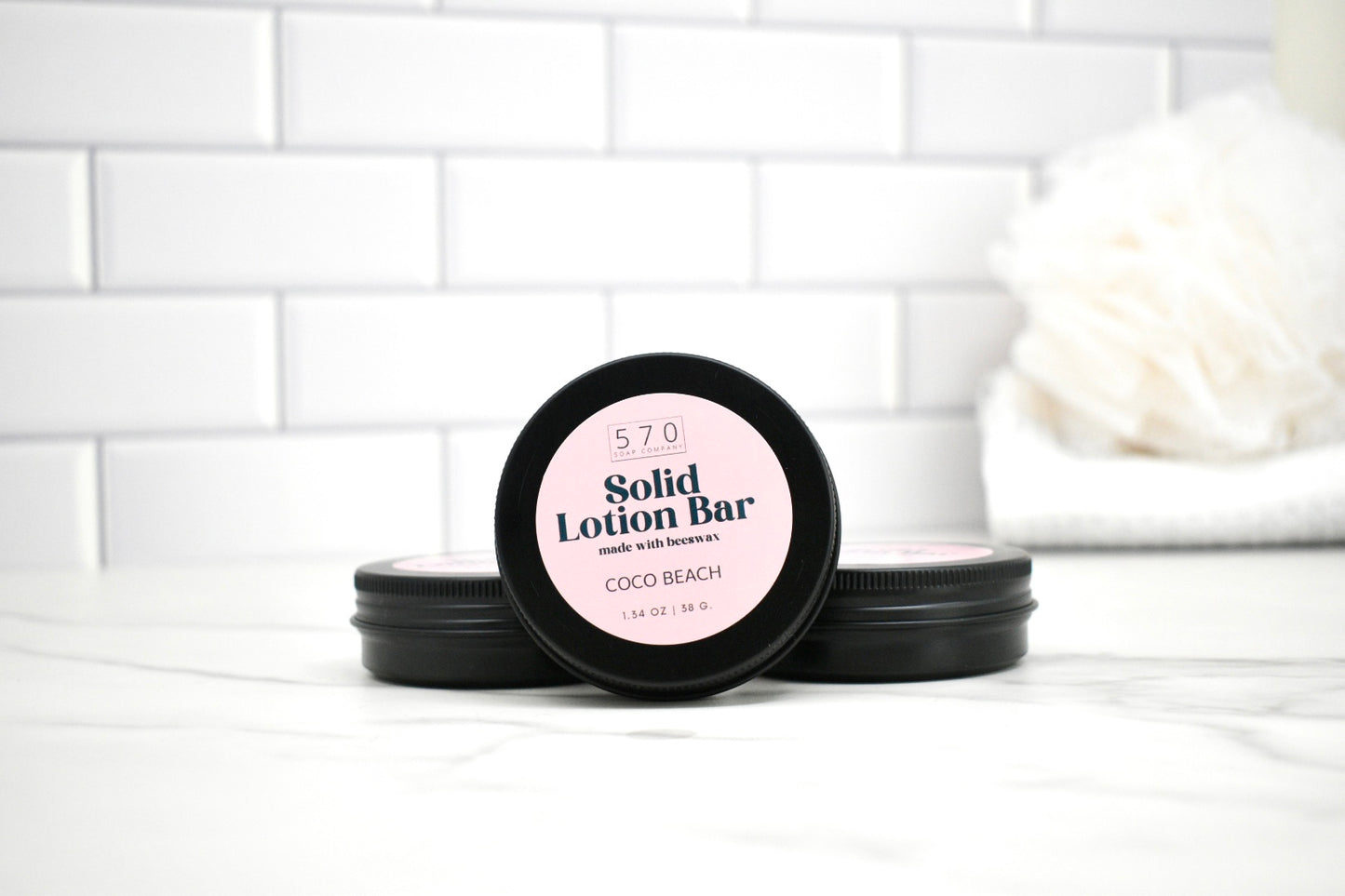 Solid lotion bar packaging with pink label on a white surface