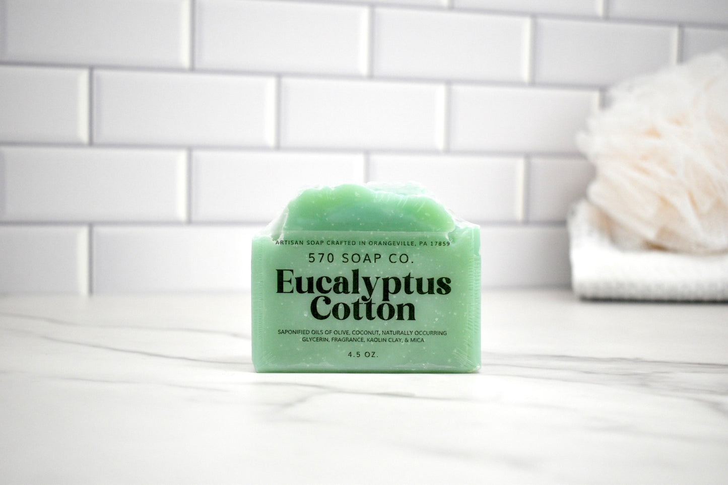 Green bar of soap with '570 Soap Co' branding on a white surface with a tiled wall background.