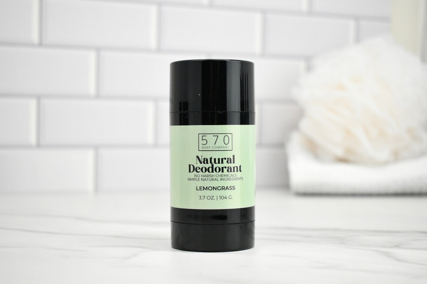 570 Natural Deodorant stick on a white surface with a tiled wall background