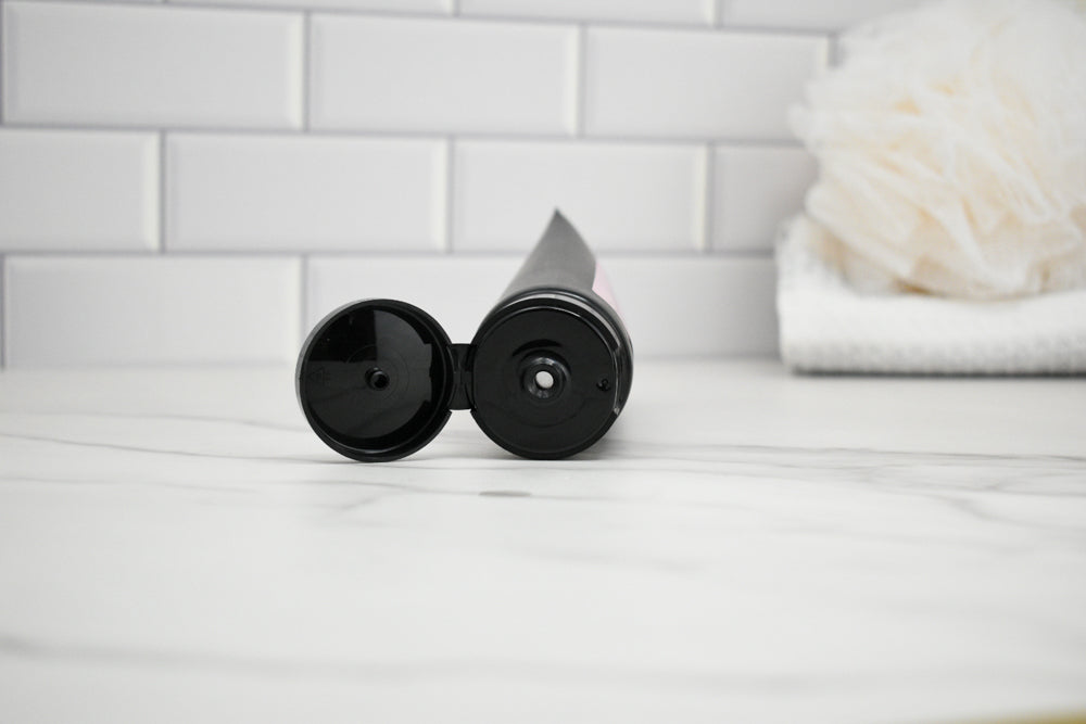 Two black cylindrical objects on a white surface with a tiled wall background