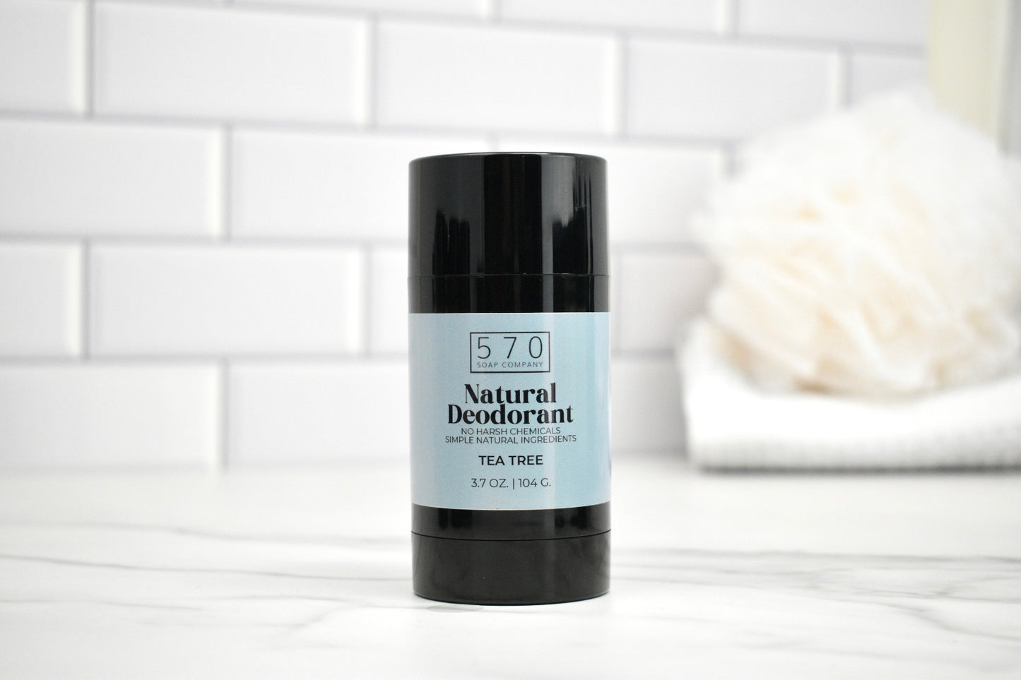 570 Natural Deodorant stick on a white surface with a tiled wall background