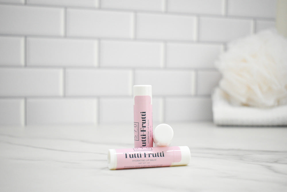 Two lip balm tubes with 'Tutti Frutti' branding on a bathroom counter.