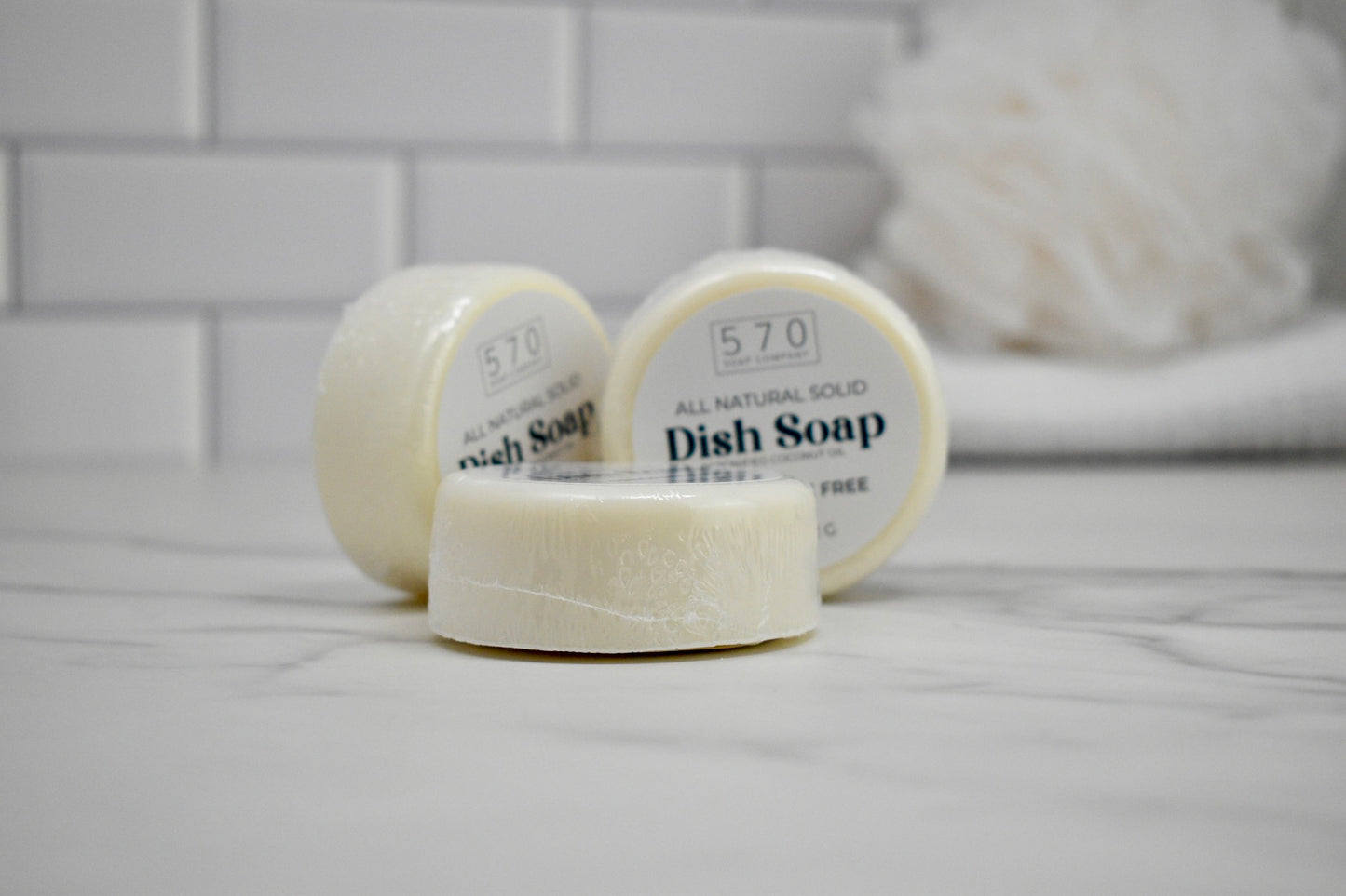 Three bars of 570 dish soap on a white surface with a blurred background