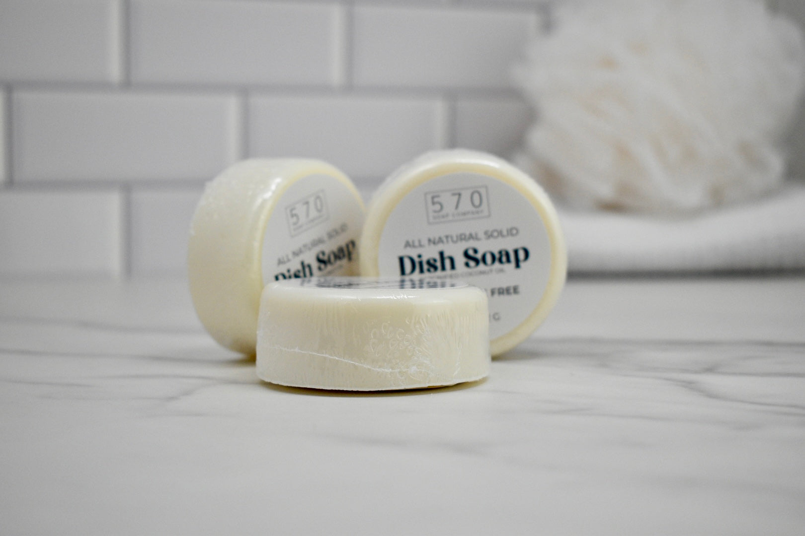 Three bars of 570 dish soap on a white surface with a blurred background