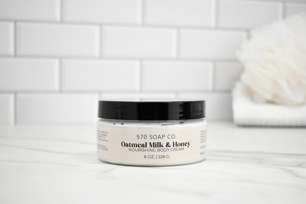 Jar of Oatmeal Milk & Honey body cream on a white surface with a tiled wall background