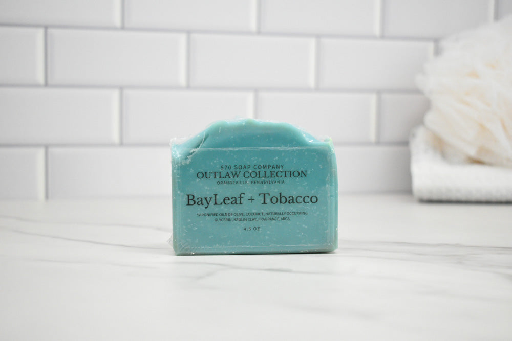 Bar of soap with 'BayLeaf + Tobacco' scent on a tiled bathroom shelf