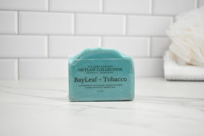 Bar of soap with 'BayLeaf + Tobacco' scent on a tiled bathroom shelf