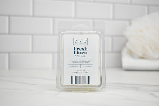 570 Fresh Linen wax melt packaging on a white surface with a tiled wall background