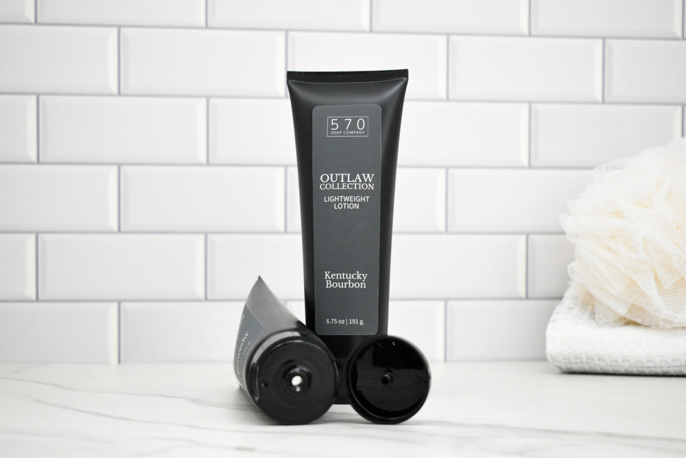 Black tube of 570 Outlaw Lotion on a white surface with a tiled wall background