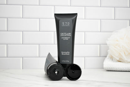 Black tube of 570 Outlaw Lotion on a white surface with a tiled wall background