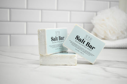Two salt bars with labels on a white surface against a tiled wall background