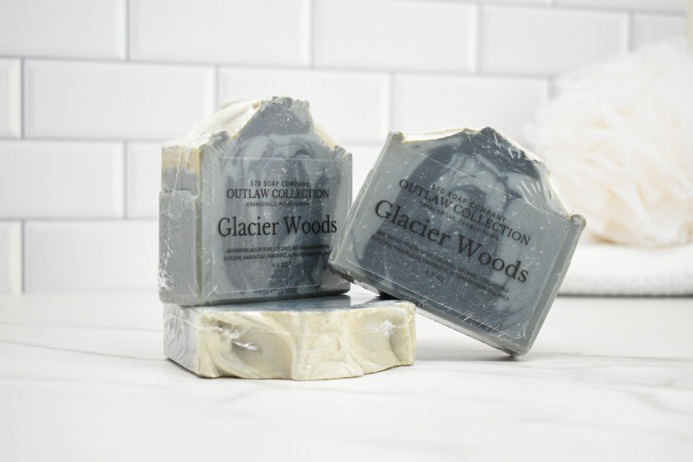 Three bars of 'Glacier Woods' soap on a white surface with a tiled wall background