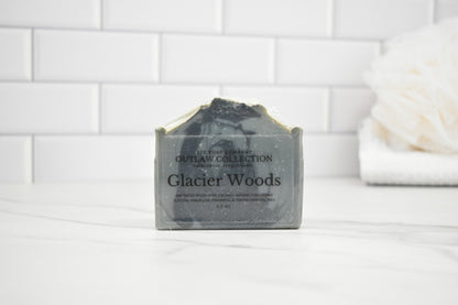 Bar of soap labeled 'Glacier Woods' on a white surface with a tiled wall background