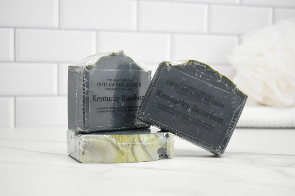 Three bars of Kentucky Bourbon soap on a white surface with a tiled wall background