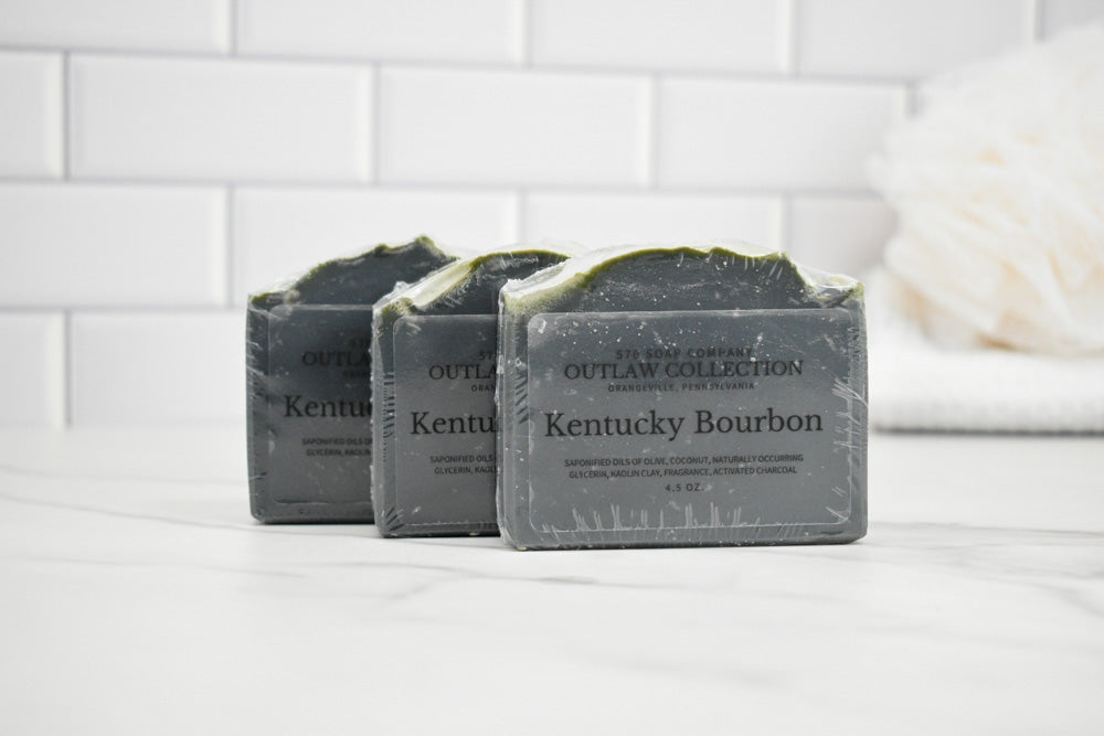 Three bars of Kentucky Bourbon soap on a white surface with a tiled wall background.