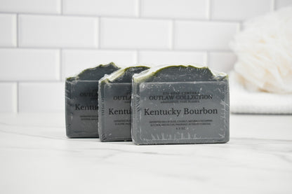 Three bars of Kentucky Bourbon soap on a white surface with a tiled wall background.