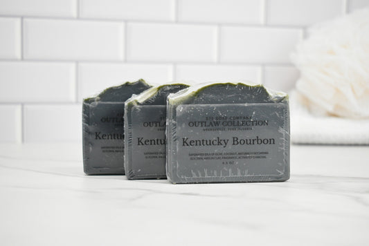 Three bars of Kentucky Bourbon soap on a white surface with a tiled wall background.