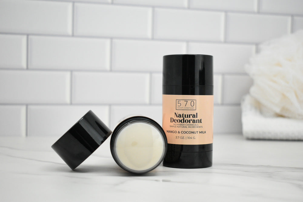 570 Natural Deodorant stick and jar on a white surface with a tiled wall background