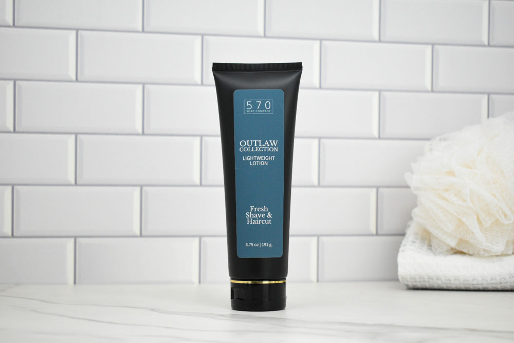 Tube of Outlaw Collection Lotion on a white tiled wall background