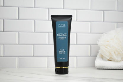 Tube of Outlaw Collection Lotion on a white tiled wall background