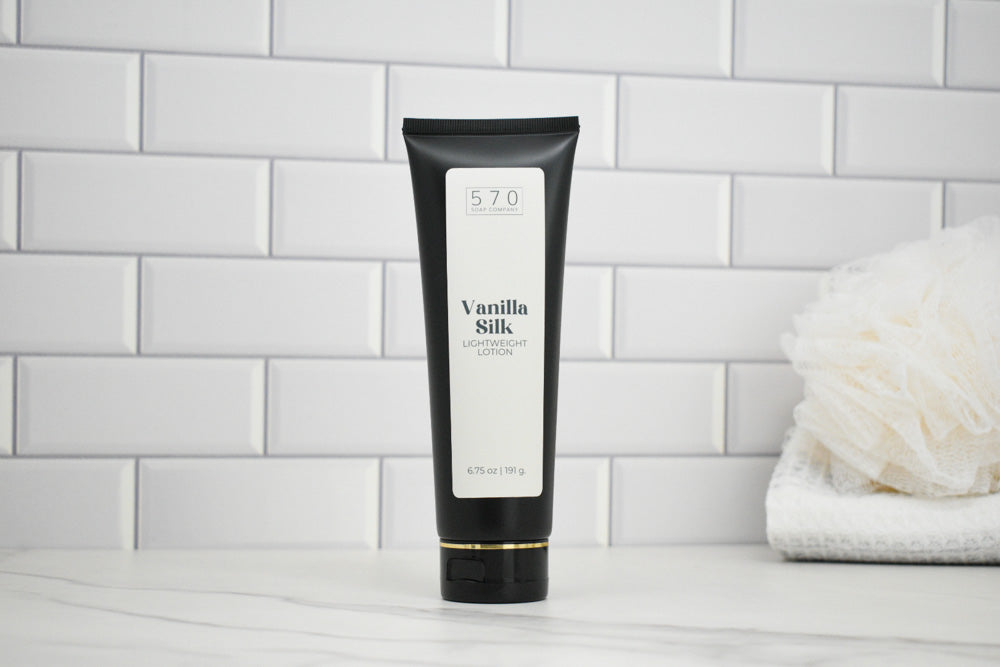 Black tube of 'Vanilla Silk' body lotion on a white tiled bathroom shelf.