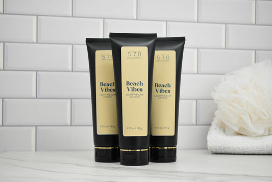 Three 'Beach Vibes' lotion tubes on a bathroom counter with a tiled wall background.