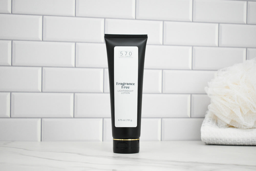 Black tube of Fragrance Free Lotion on a white surface with a tiled wall background