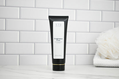 Black tube of Fragrance Free Lotion on a white surface with a tiled wall background