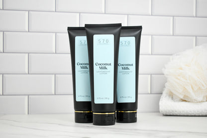 Three tubes of Coconut Milk body lotion on a white surface with a tiled wall background.