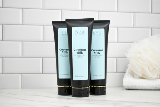 Three tubes of Coconut Milk body lotion on a white surface with a tiled wall background.