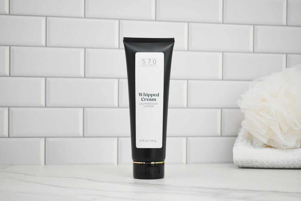 Black tube of whipped cream lotion on a white tiled wall background