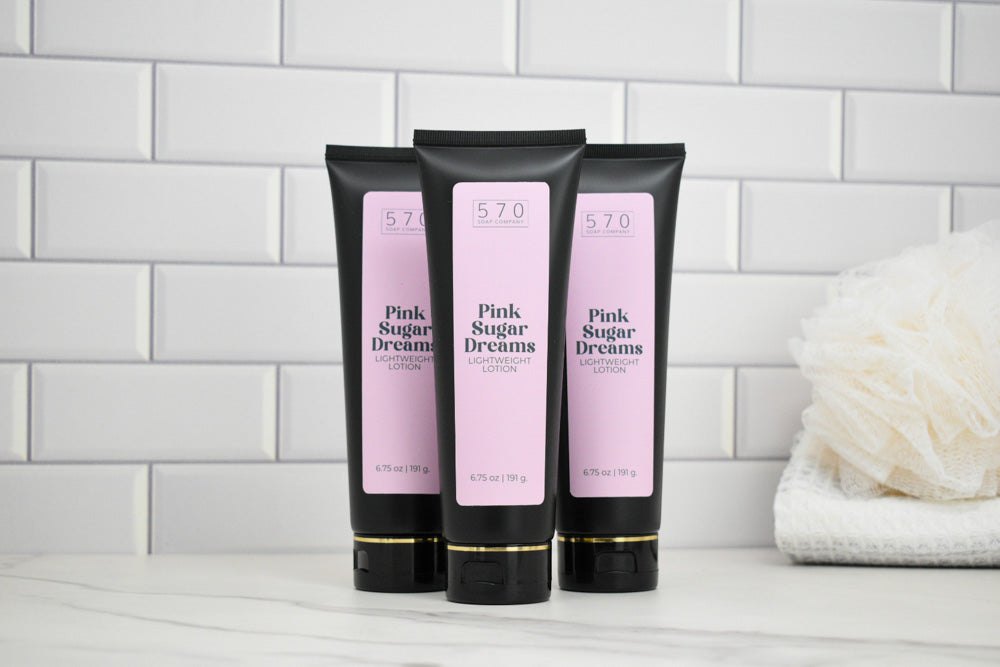 Three tubes of 'Pink Sugar Dreams' lotion on a white surface with a tiled wall background.