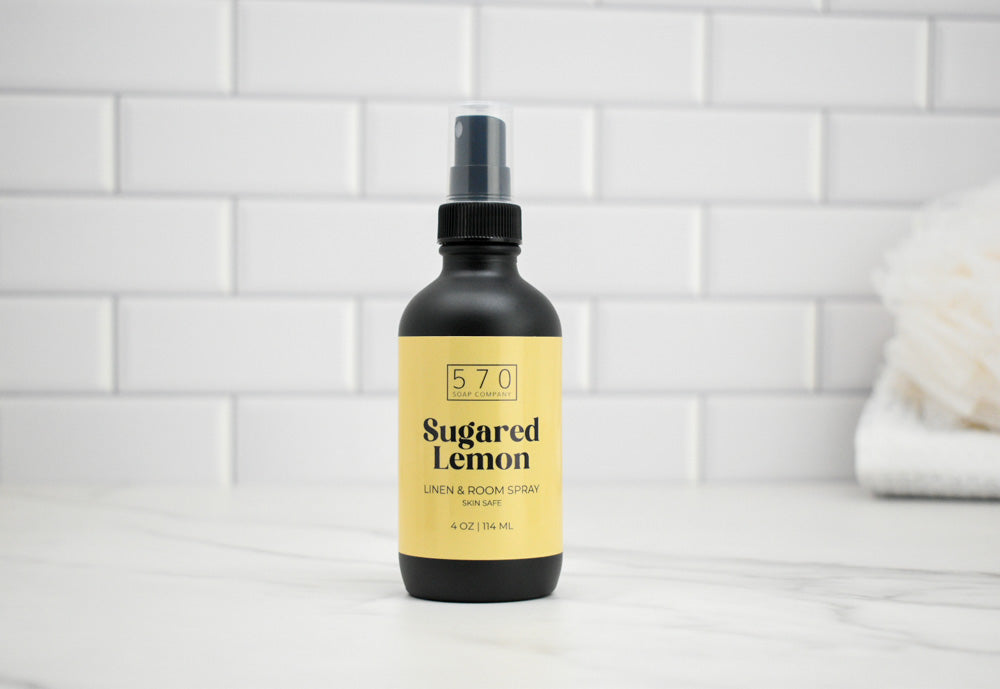 Black spray bottle with yellow label on a white tiled wall background