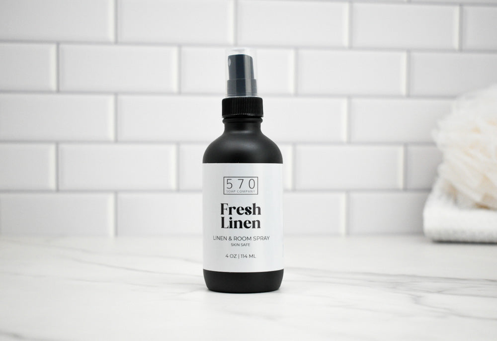Bottle of 570 Fresh Linen spray on a white tiled bathroom counter.