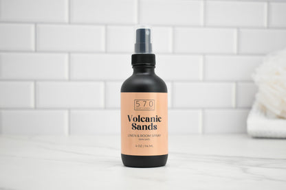 Bottle of '570 Volcanic Sands' linen and room spray on a white tiled background