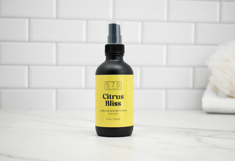 Bottle of 570 Citrus Bliss linen and room spray on a white tiled wall background