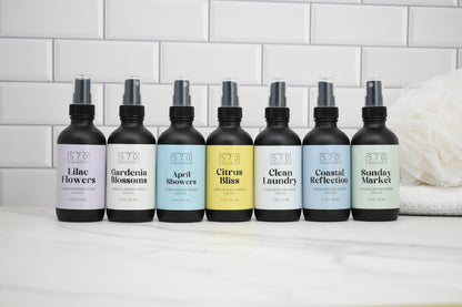 Row of 8 bottles with labels on a white surface against a tiled wall background