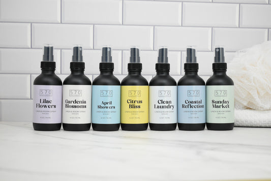 Row of 8 bottles with labels on a white surface against a tiled wall background