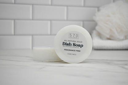 All-natural solid dish soap container on a bathroom counter with a tiled wall background.