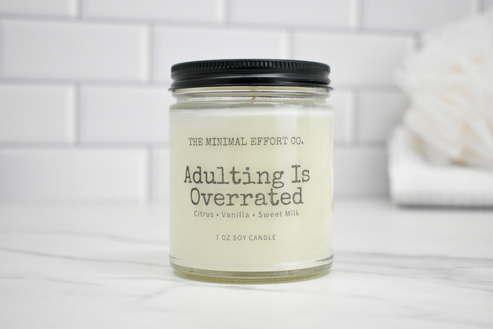 Candle jar with 'The Minimal Effort Co.' label on a white surface