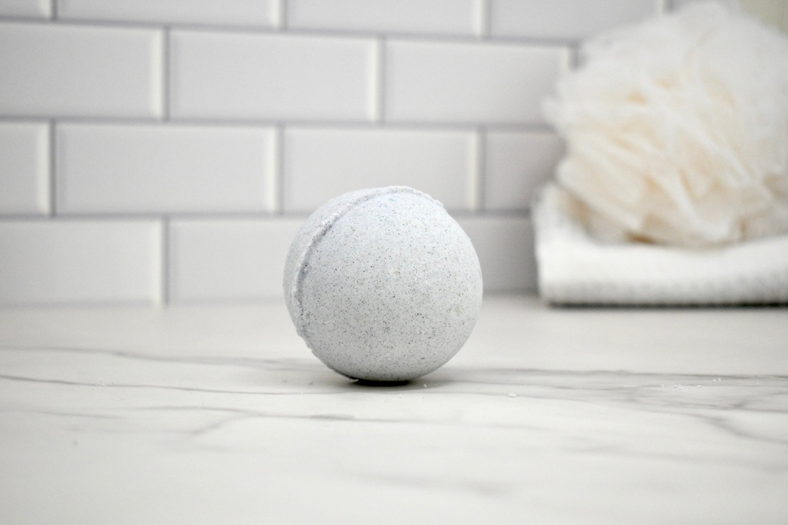 Bath bomb on a bathroom counter with a white tiled wall in the background