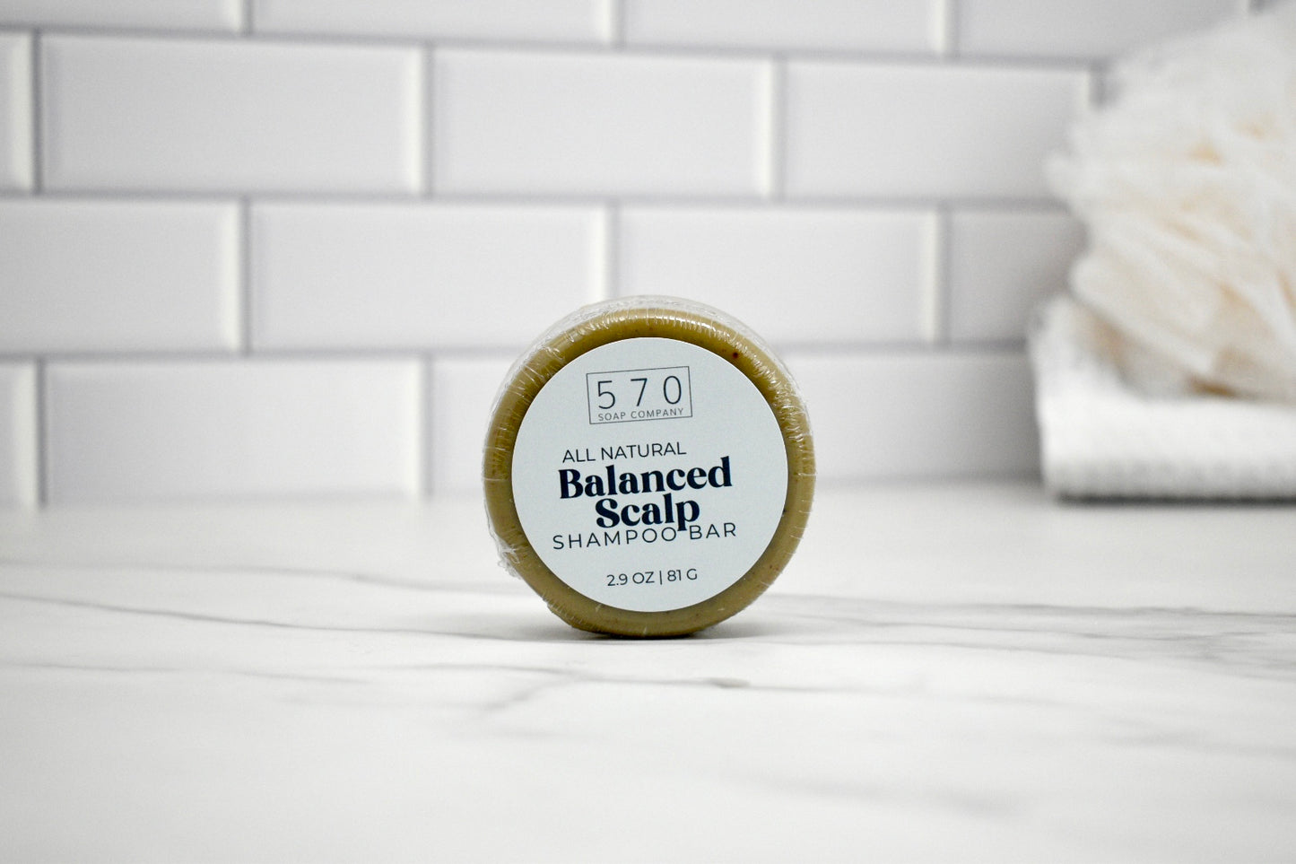 Bar of soap with a label on a white surface against a tiled wall background