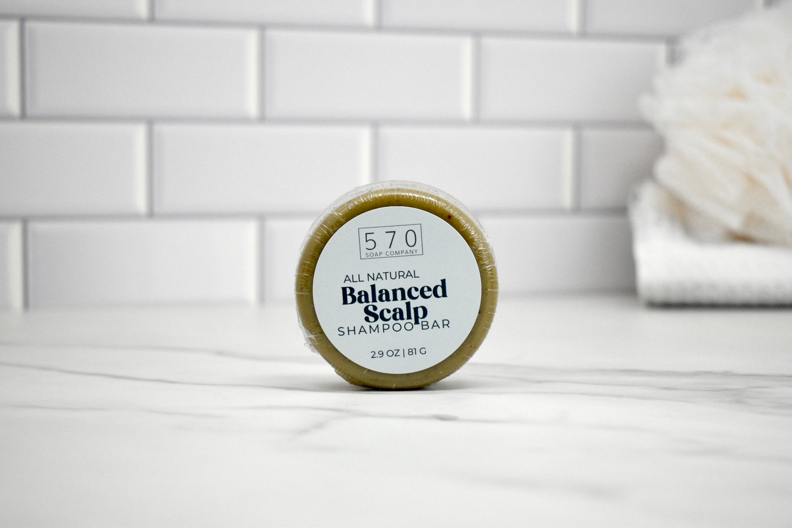 Bar of soap with a label on a white surface against a tiled wall background