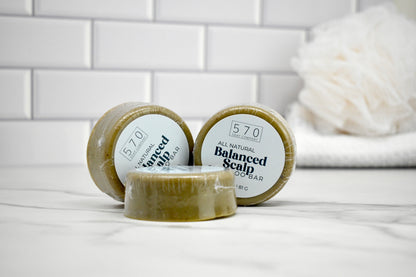 Three soap bars with '570' branding on a white surface with a tiled wall background.