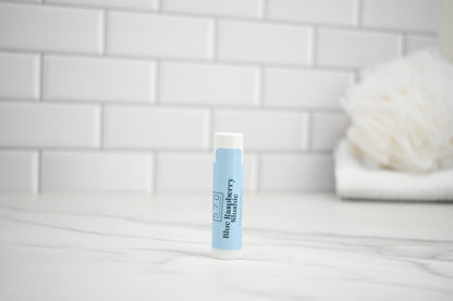 Lip balm with blue label on a white surface against a tiled wall background